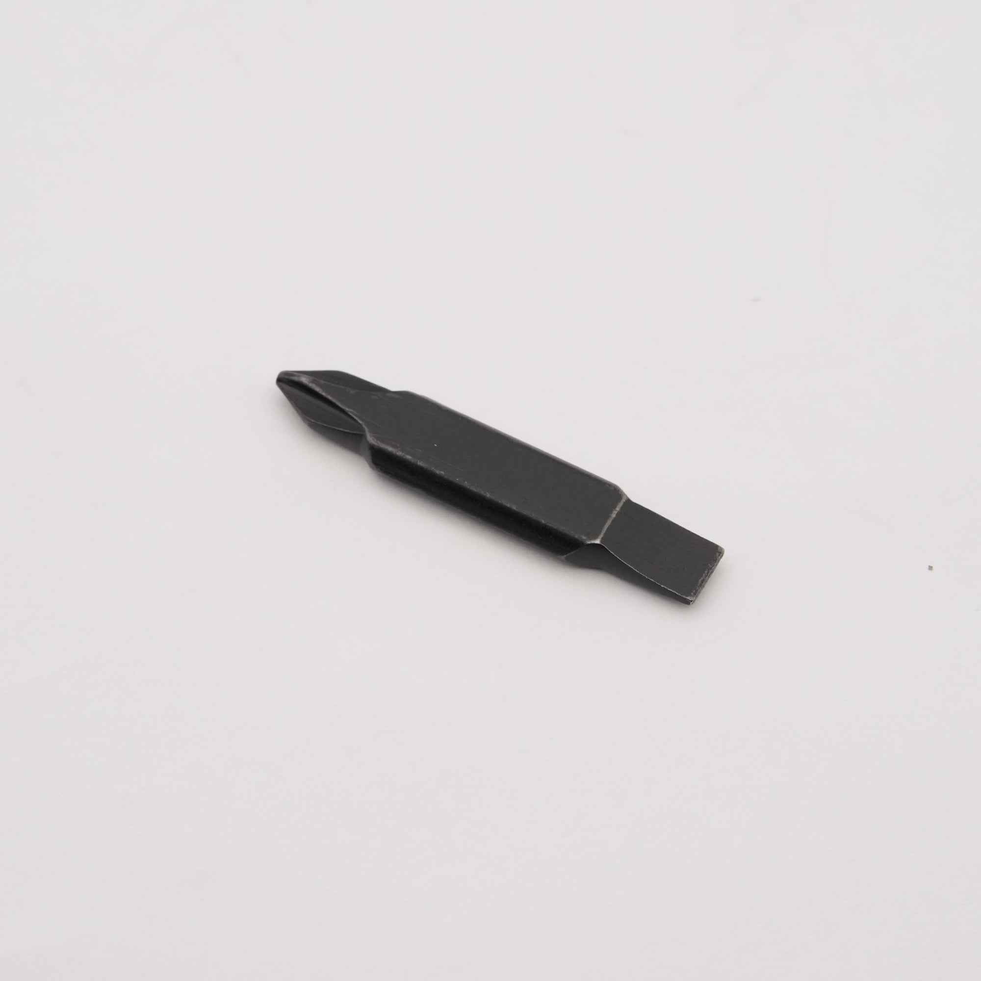 A small black flathead screwdriver bit with a slotted center, shown on a plain light gray background.